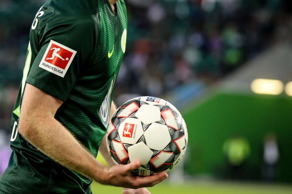 Logo de la Bundesliga en la camiseta de un jugador y el balón en sus manos