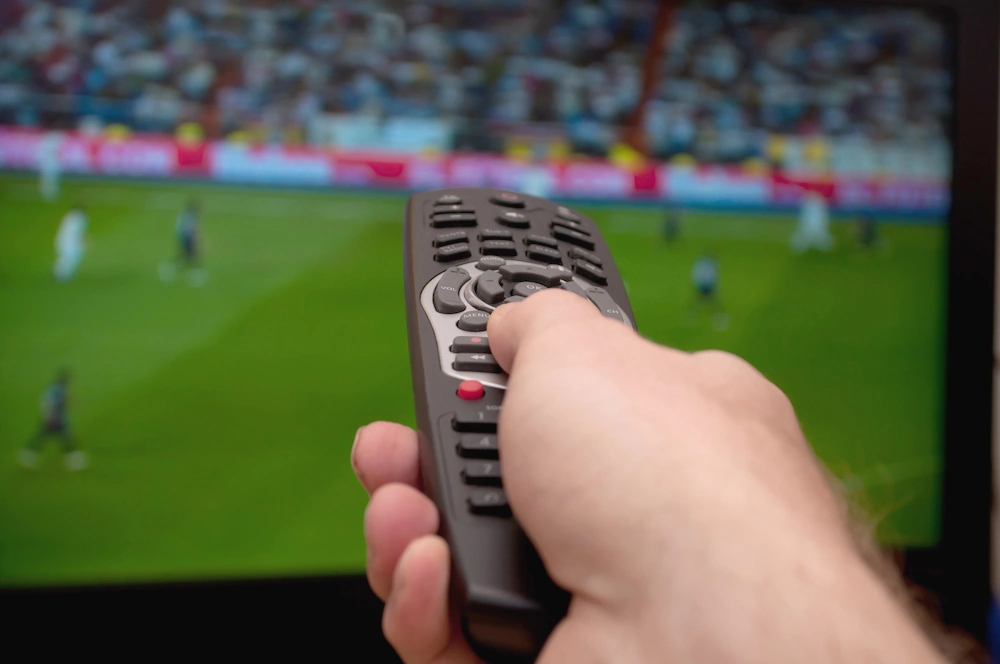 Mando a distancia apuntando a un televisor que muestra fútbol